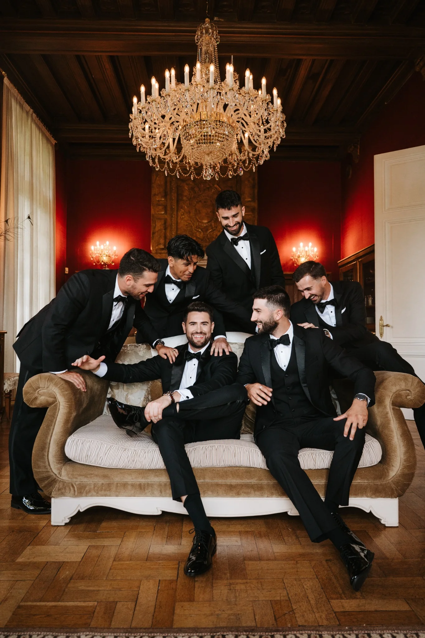 Wedding party in black tuxedos gathered around a sofa